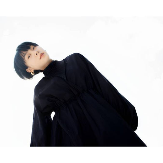 asian woman with short edgy haircut wearing a long-sleeve black turtle neck with a wide flowing waist