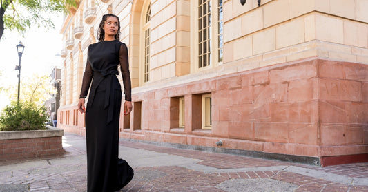 woman getting dressed in a long-sleeve black formal dress