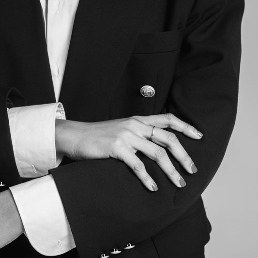 person wearing a long-sleeve black suit jacket with a white shirt underneath, with painted fingernails